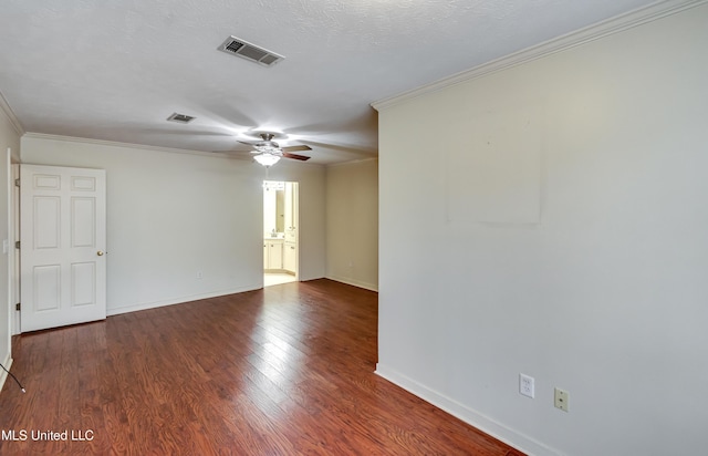 empty room featuring baseboards, visible vents, wood finished floors, and ornamental molding