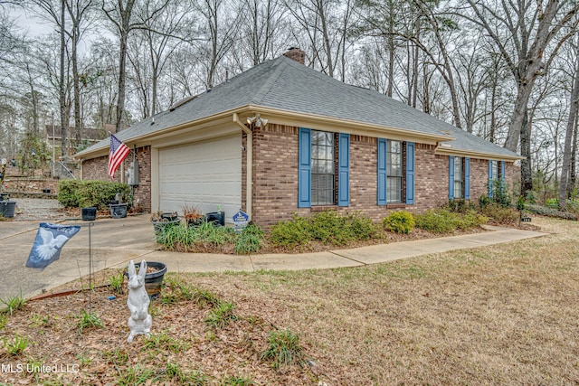 view of side of home with brick siding, roof with shingles, a chimney, an attached garage, and driveway