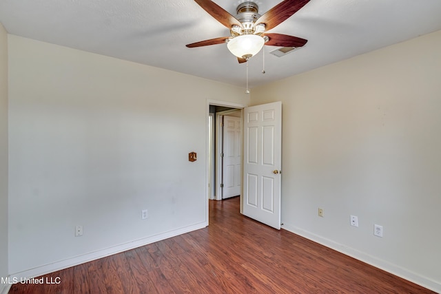 empty room with a ceiling fan, dark wood finished floors, and baseboards