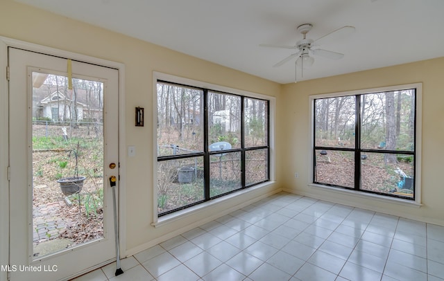 interior space featuring a ceiling fan, a wealth of natural light, and baseboards