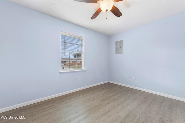 spare room with wood-type flooring, electric panel, and ceiling fan