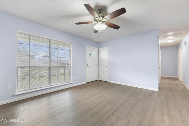 empty room featuring ceiling fan, a textured ceiling, and light hardwood / wood-style floors