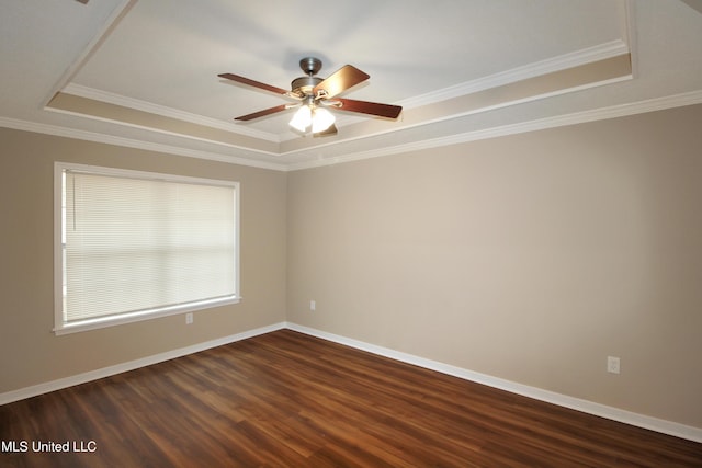 spare room with a tray ceiling, crown molding, ceiling fan, and dark wood-type flooring