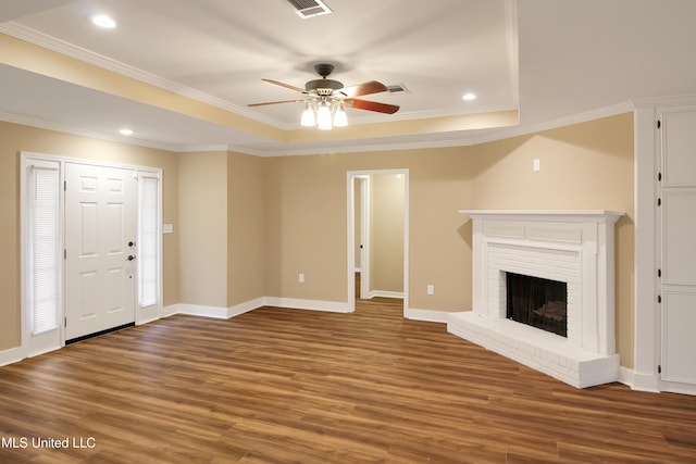 unfurnished living room with a tray ceiling, ceiling fan, a fireplace, and crown molding