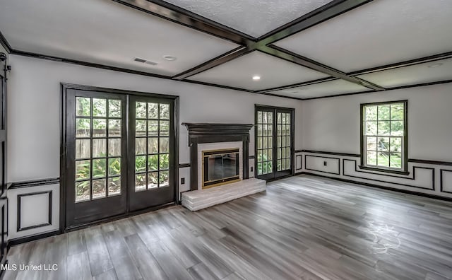 unfurnished living room with french doors, coffered ceiling, a brick fireplace, and light wood-type flooring