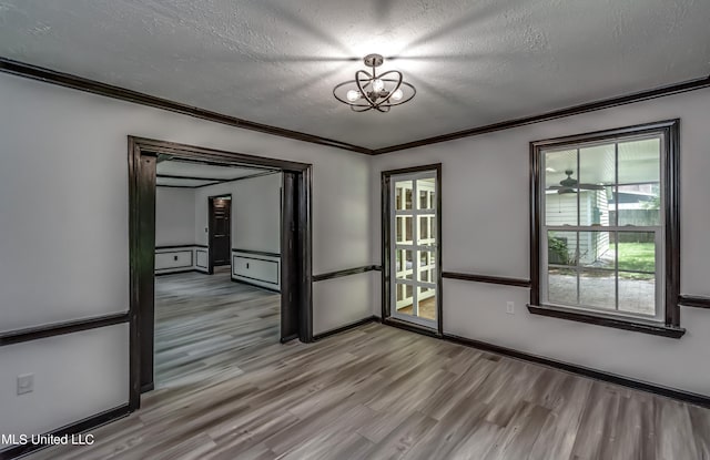 spare room with ornamental molding, a textured ceiling, and light hardwood / wood-style floors