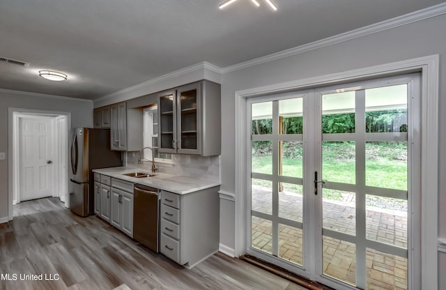 kitchen featuring light hardwood / wood-style floors, stainless steel appliances, ornamental molding, and gray cabinets