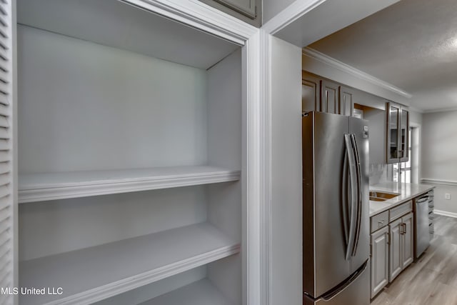 kitchen with crown molding, stainless steel appliances, and light wood-type flooring