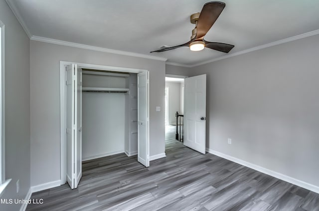 unfurnished bedroom with a closet, ceiling fan, hardwood / wood-style flooring, and crown molding