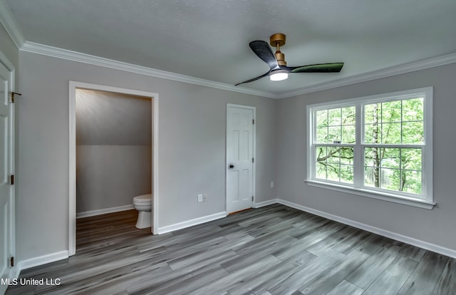 unfurnished bedroom featuring ensuite bathroom, ornamental molding, light wood-type flooring, and ceiling fan