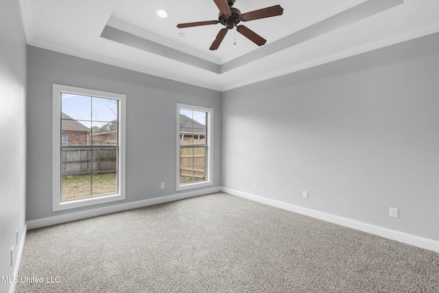 unfurnished room featuring carpet, a raised ceiling, ornamental molding, ceiling fan, and baseboards