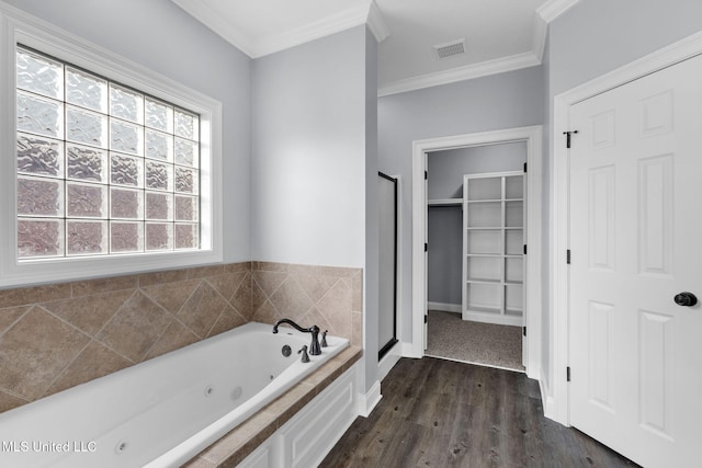 bathroom featuring wood finished floors, visible vents, a spacious closet, a tub with jets, and crown molding