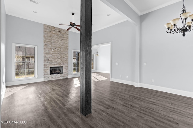 unfurnished living room with crown molding, dark wood finished floors, a stone fireplace, and baseboards