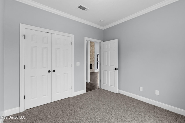 unfurnished bedroom with baseboards, visible vents, ornamental molding, carpet floors, and a closet