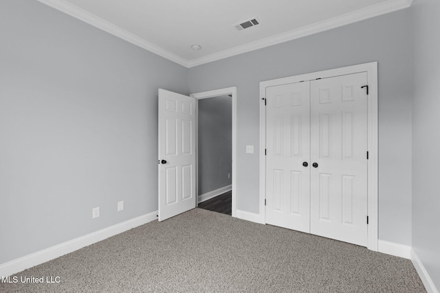 unfurnished bedroom featuring baseboards, visible vents, carpet, crown molding, and a closet