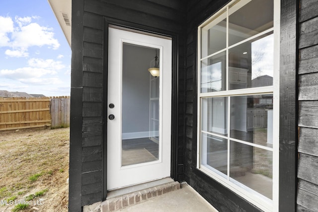 doorway to property featuring visible vents and fence