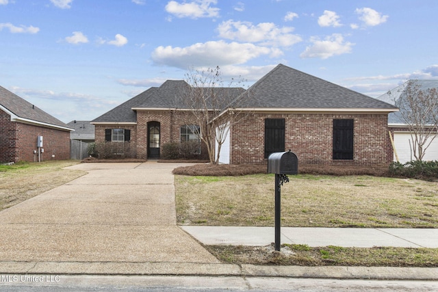 view of front of property featuring driveway, roof with shingles, a front yard, and brick siding