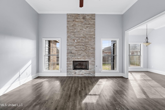 unfurnished living room with baseboards, a stone fireplace, wood finished floors, and crown molding