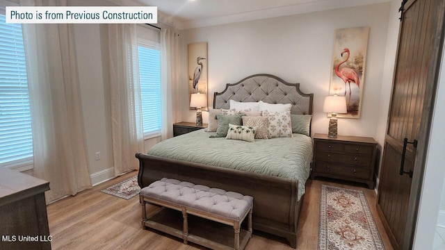 220 W Ave, Long Beach, MS 39560 - bedroom with light wood finished floors, a barn door, and baseboards