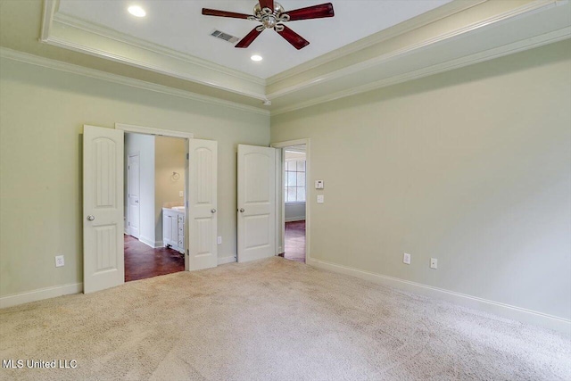 unfurnished bedroom with ceiling fan, a tray ceiling, crown molding, and carpet