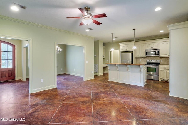 kitchen featuring ornamental molding, a kitchen island, decorative light fixtures, ceiling fan, and stainless steel appliances