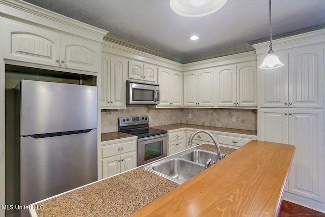 kitchen with decorative backsplash, ornamental molding, stainless steel appliances, sink, and decorative light fixtures