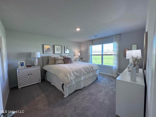 bedroom with a textured ceiling and dark carpet