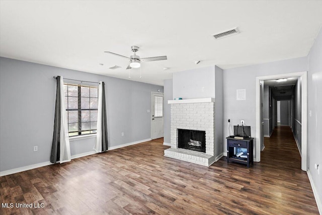 unfurnished living room featuring dark wood-type flooring, a brick fireplace, and ceiling fan