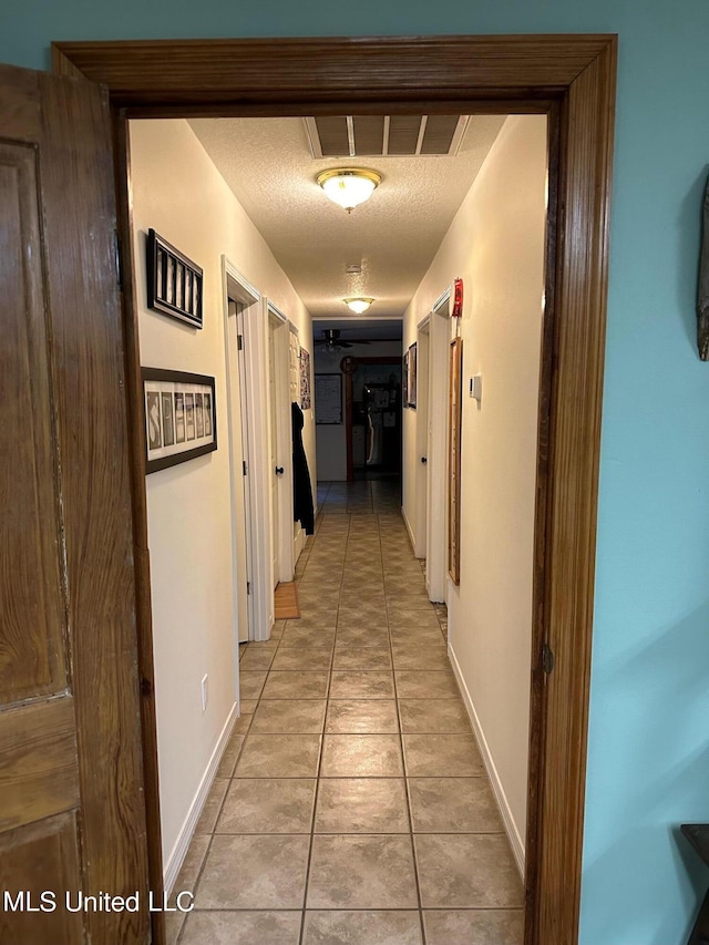 hallway featuring light tile patterned floors and a textured ceiling