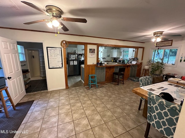 interior space with black refrigerator, tile patterned floors, ceiling fan, and crown molding