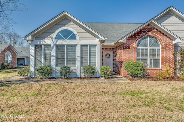 single story home featuring roof with shingles, brick siding, and a front lawn