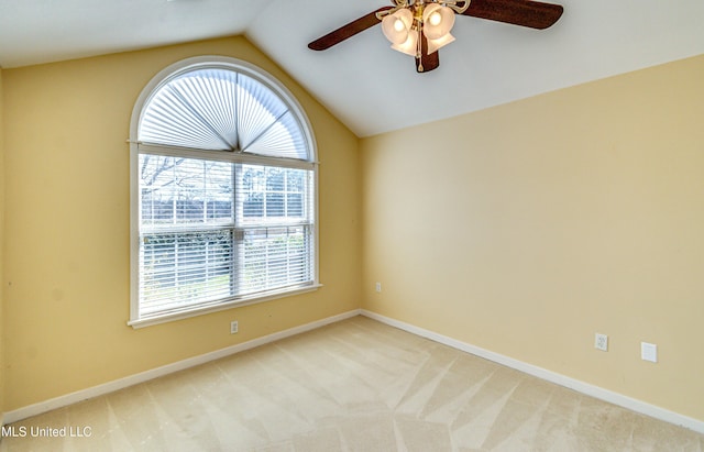 empty room with ceiling fan, baseboards, vaulted ceiling, and light colored carpet