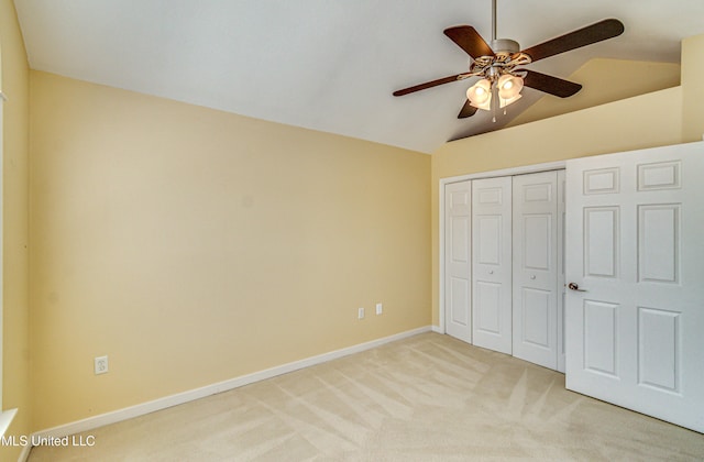 unfurnished bedroom with baseboards, light colored carpet, lofted ceiling, ceiling fan, and a closet