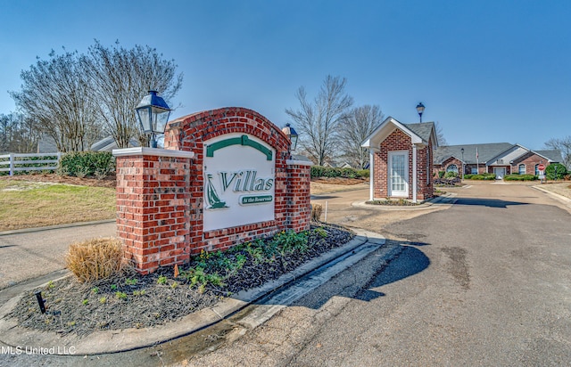 community / neighborhood sign featuring fence