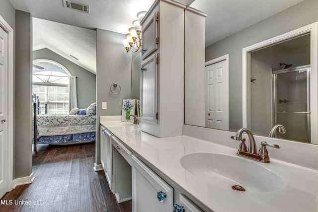 ensuite bathroom featuring double vanity, visible vents, a stall shower, connected bathroom, and a sink