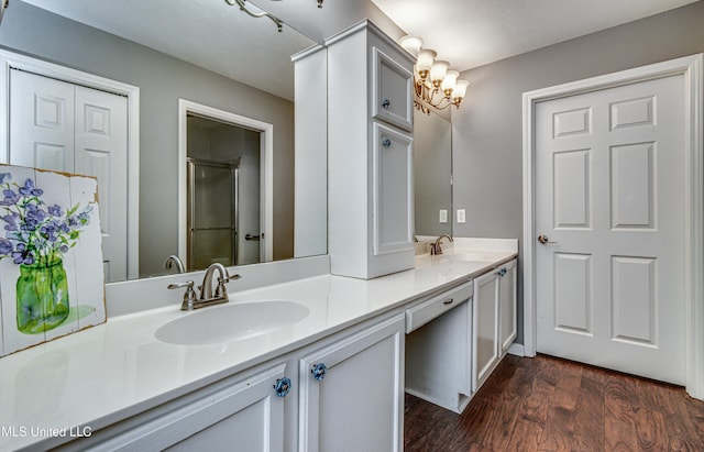 bathroom featuring double vanity, a shower with door, a sink, and wood finished floors