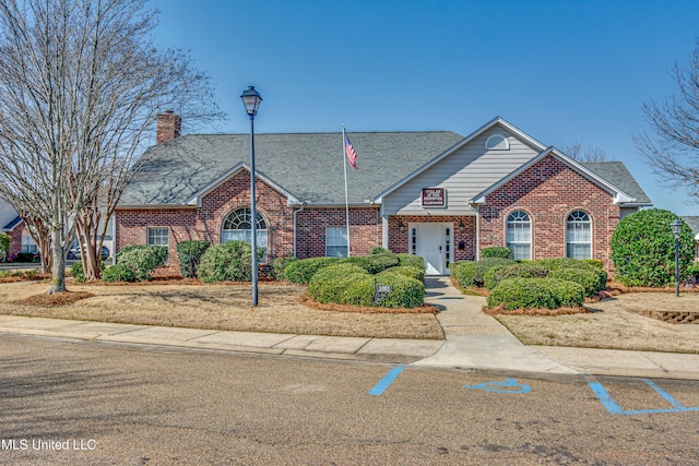 view of front facade featuring a shingled roof and brick siding