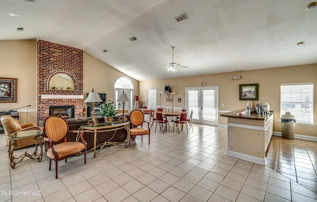 living room featuring light tile patterned floors, plenty of natural light, visible vents, and a brick fireplace