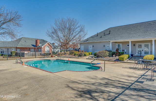 view of swimming pool featuring a patio, french doors, fence, and a fenced in pool