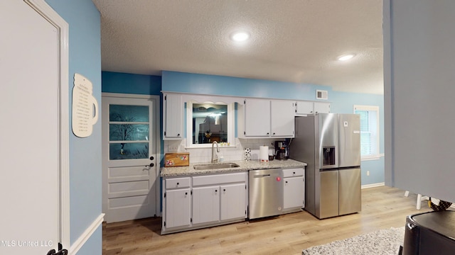 3902 S Windermere Dr, Nesbit, MS 38651 - kitchen featuring stainless steel appliances, a sink, light wood-type flooring, a textured ceiling, and white cabinets