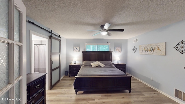 3902 S Windermere Dr, Nesbit, MS 38651 - bedroom featuring a barn door, light wood-type flooring, a textured ceiling, a ceiling fan, and baseboards