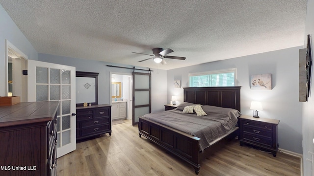 3902 S Windermere Dr, Nesbit, MS 38651 - bedroom with a barn door, light wood-type flooring, a textured ceiling, ceiling fan, and baseboards