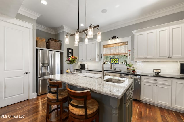 kitchen with appliances with stainless steel finishes, a sink, tasteful backsplash, a kitchen island with sink, and dark stone counters