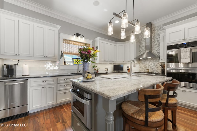 kitchen with stainless steel appliances, backsplash, dark wood finished floors, a kitchen bar, and crown molding