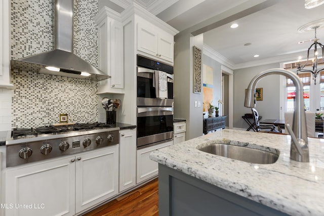 kitchen with wall chimney range hood, stainless steel appliances, a sink, crown molding, and dark wood-style floors