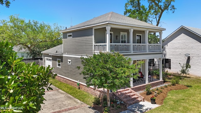 view of front of property featuring roof with shingles, a balcony, and a front lawn
