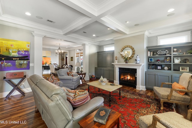 living room with decorative columns, dark wood-style floors, ornamental molding, a chandelier, and a glass covered fireplace