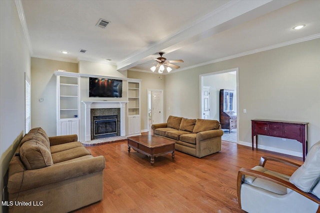 living room with baseboards, visible vents, a glass covered fireplace, wood finished floors, and crown molding