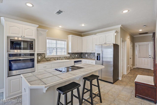 kitchen with tile countertops, a sink, visible vents, white cabinetry, and appliances with stainless steel finishes