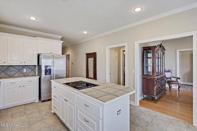 kitchen with tile countertops, black electric stovetop, decorative backsplash, ornamental molding, and stainless steel fridge